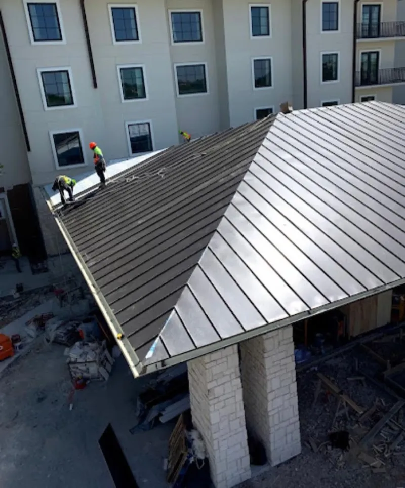 Crew installing standing seam metal roof panels on a commercial project in Richmond